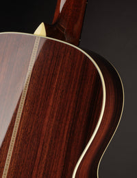 Close-up of a wooden acoustic guitar with a dark brown finish on a black background