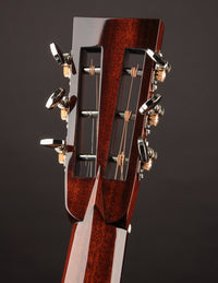 Close-up of a guitar headstock with tuning pegs on a dark background