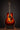 Acoustic guitar on a stand against a dark background