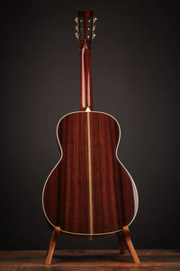 Acoustic guitar on a stand against a dark background