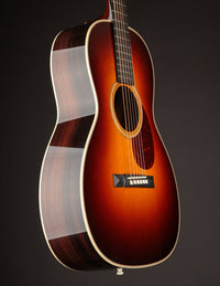 Acoustic guitar with a sunburst finish on a dark background, side view