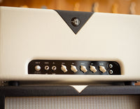 Close-up of a guitar amplifier with control knobs and brand logo.