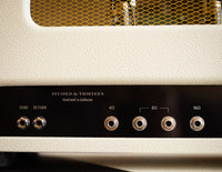Close-up of a vintage-style amplifier with control knobs and labels.