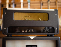 Back view of guitar amplifier with guitars in the background