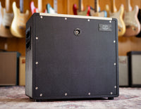 Back view of Divided by Thirteen speaker cabinet with guitars in the background