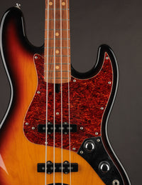 A close up of a used Lakland Shoreline Series electric bass guitar with a sunburst finish and tortoise pickguard. 