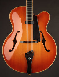 Archtop guitar with a sunburst finish on a dark background