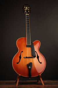 Archtop guitar on a stand against a dark background
