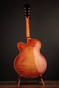 The back of an archtop guitar artfully displayed on a stand against a dark background