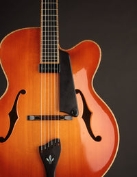 Close-up of a sunburst archtop guitar with a dark background