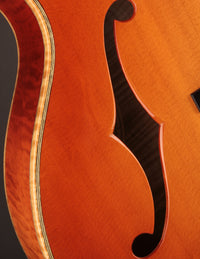 Close-up of an archtop guitar's f-hole and maple binding.