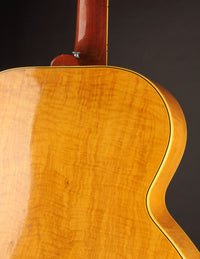 Close-up of a wooden electric guitar with a dark background