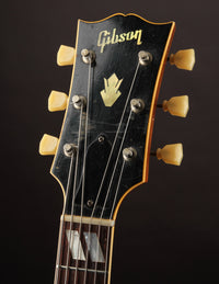 Gibson guitar headstock with tuning pegs on a dark background
