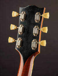 Close-up of a guitar headstock with tuning pegs on a dark background