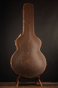 Vintage guitar case on a stand against a dark background