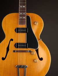Close-up of a vintage-style electric guitar with a dark brown finish on a black background