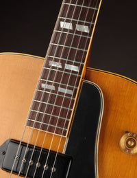 Close-up of a guitar neck with a wooden body on a black background
