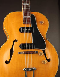 Close-up of a vintage-style electric guitar with a dark brown background