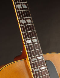 Close-up of a guitar neck with fretboard and soundhole on a dark background