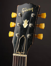 Gibson guitar headstock with tuning pegs on a dark background