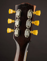 Close-up of a guitar headstock with six tuning pegs on a dark background