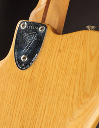 Close-up of a Fender guitar with a visible serial number on the neck plate