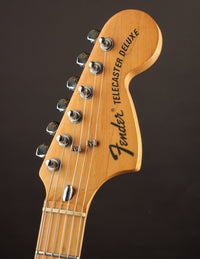 Close-up of a Fender Telecaster Deluxe guitar headstock on a dark background