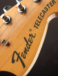 Close-up of a Fender Telecaster guitar headstock with visible branding.