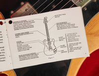 Technical diagram of a guitar on a white card held over a guitar
