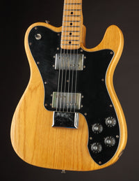 Electric guitar with a black pickguard and wooden body on a dark background