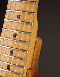 Close-up of a guitar neck with frets and strings on a dark background