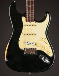 Black 1968 Fender Stratocaster electric guitar with a white pickguard on a dark background