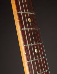 Close-up of a guitar neck with frets and strings on a dark background
