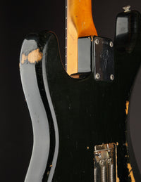 Close-up of a black 1968 Fender Stratocaster electric guitar with visible wear on the body against a dark background.