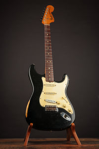 Black 1968 Fender Stratocaster on a stand against a dark background