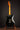 Black 1968 Fender Stratocaster on a stand against a dark background, back view 
