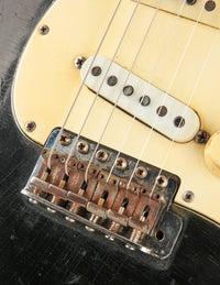 Close-up of a guitar bridge and strings on a Black 1968 Fender Stratocaster