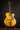 Blonde archtop guitar on a stand against a dark background