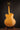 Back view of a blonde archtop guitar on a stand against a dark background