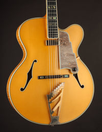 Blonde archtop guitar on a dark background