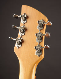 Close-up of a guitar headstock with tuning pegs on a dark background