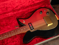 Electric guitar with gold pickguard in a case with red interior 