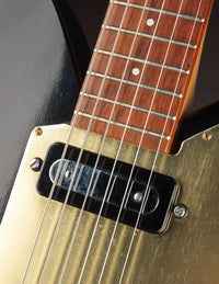 Close-up of a guitar's neck and pickguard with a dark background