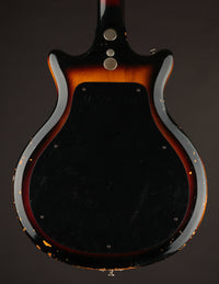Back view of a bass guitar with a dark finish on a black background