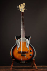 Electric bass guitar with a sunburst finish on a stand against a dark background
