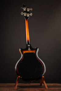 Electric bass guitar on a stand against a dark background