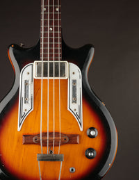 Vintage electric bass guitar with a sunburst finish on a dark background