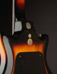 Vintage electric bass guitar with a sunburst finish on a dark background, close up of back