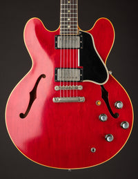 Red electric guitar with a black pickguard on a dark background