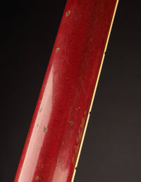 Close-up of a red guitar neck with a dark background